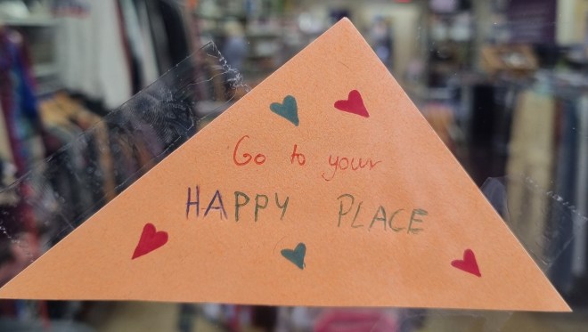 orange triangular message with hearts and the words 'go to your happy place' in the Mind Cambridge window for Time To Talk Day 2026 
